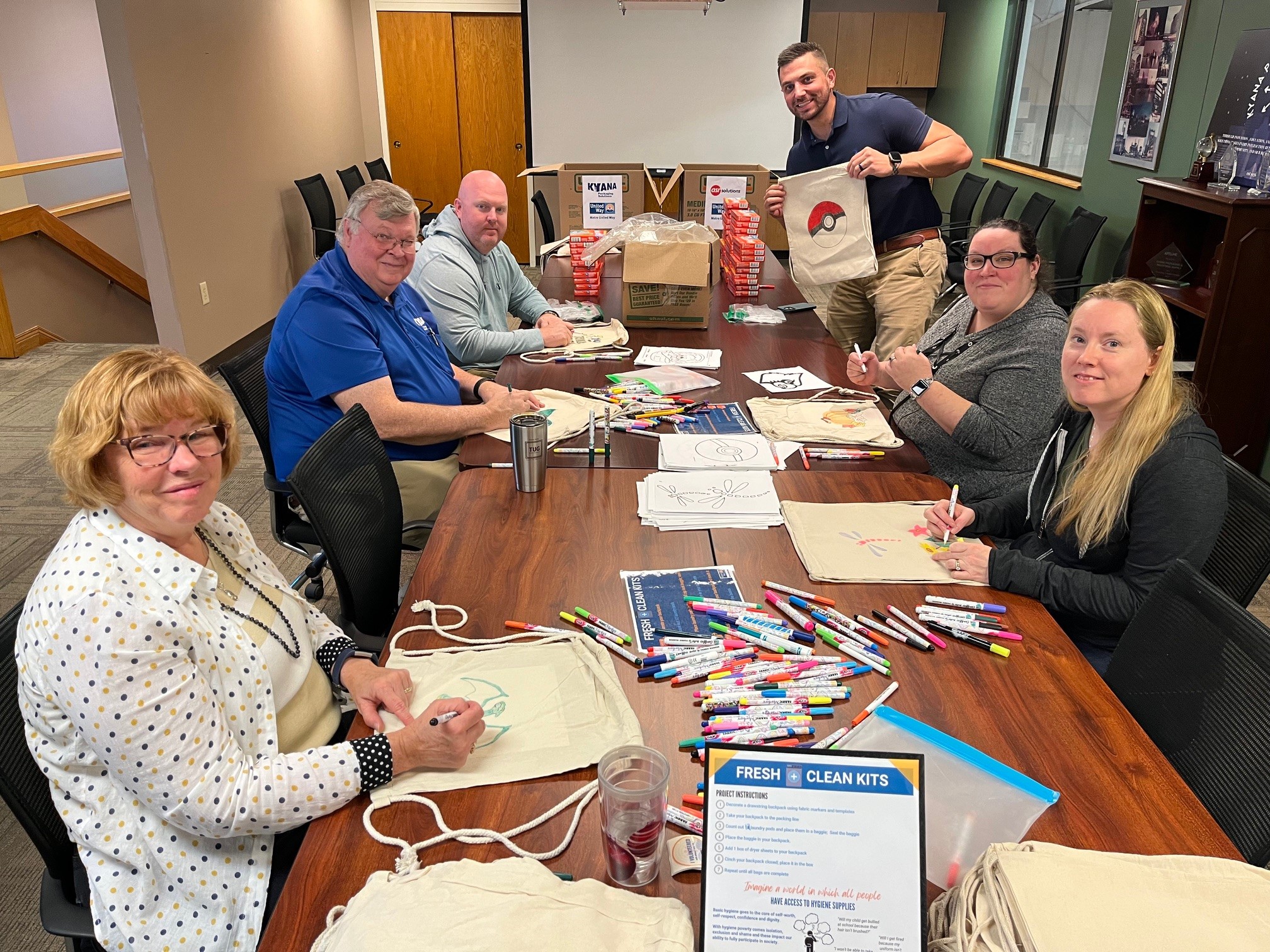 Kyana employees decorating and assembling laundry essentials into bags for a charity event